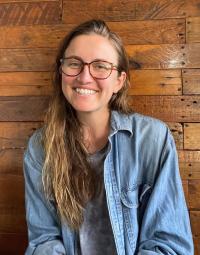 A young woman wearing glasses smiles